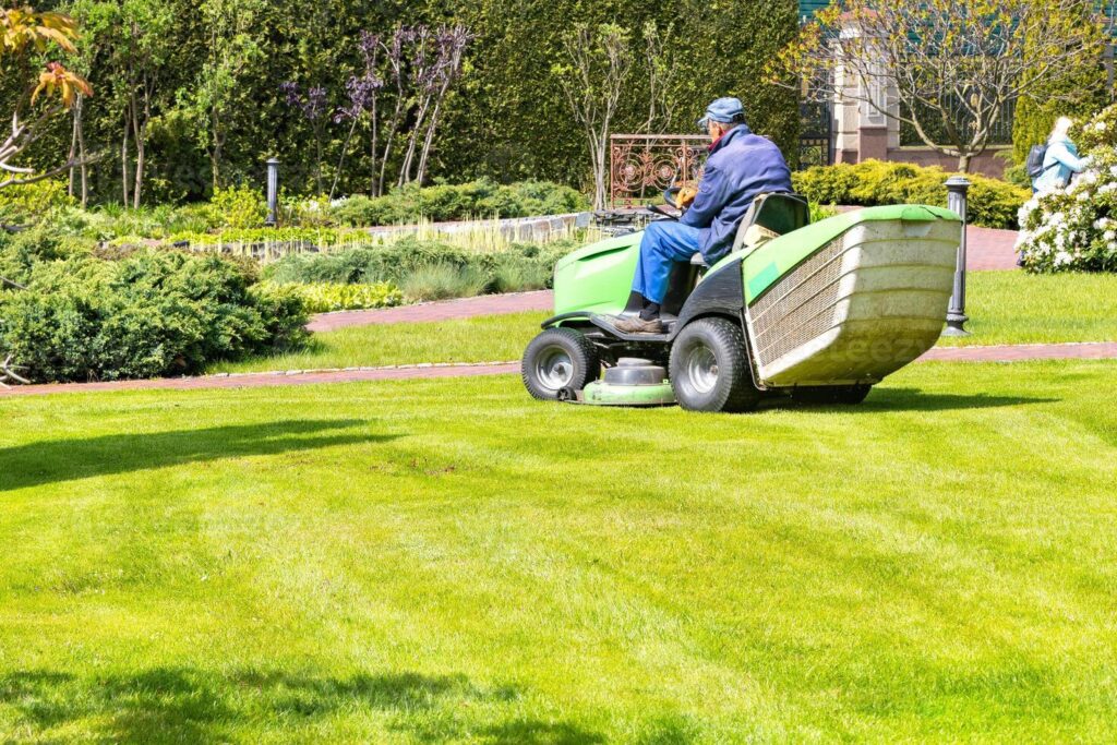 a gardener uses a tractor type industrial lawn mower to cut the grass professional gardening details photo
